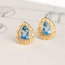 Load image into Gallery viewer, Pair of 18k yellow gold pear-shaped aquamarine stud earrings with hand-engraved texture and diamond borders.

