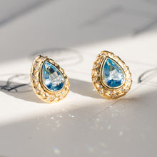 Load image into Gallery viewer, Pair of 18k yellow gold pear-shaped aquamarine stud earrings with hand-engraved texture and diamond borders.
